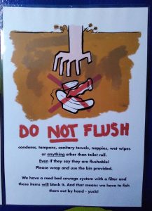 a sign showing a hand descending into sewage to pull out a tampon, a condom and a sanitary towel, all with a big red cross over them. Underneath the image is a list of what mustn't be flushed at Beech Hill